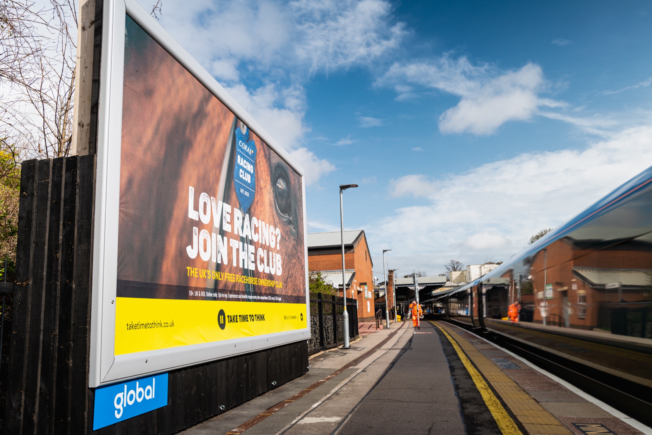 “Love racing? Join the club” billboard on the station platform
