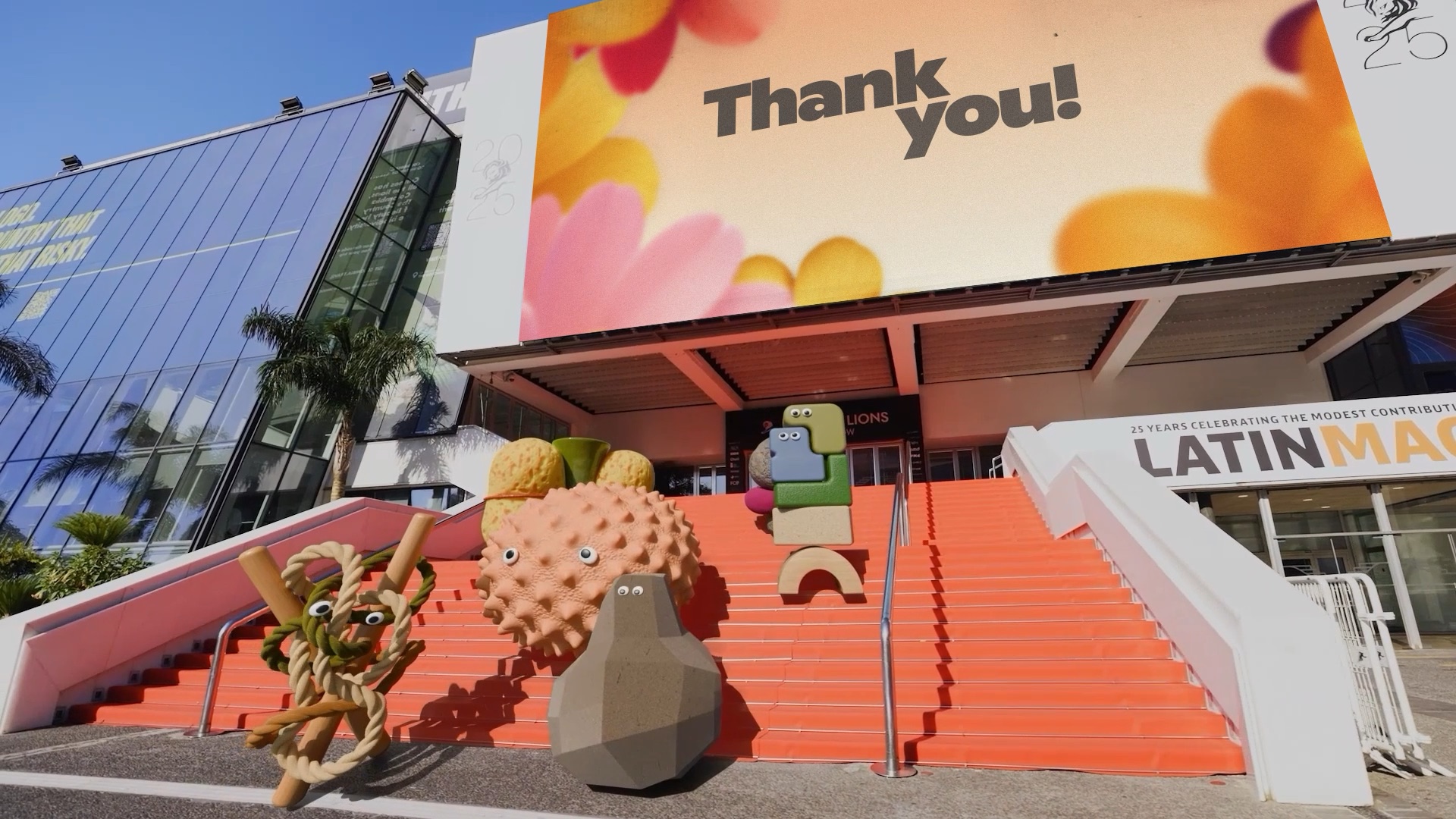 Creative Demons on the red steps of the Palais, under a Thank you banner